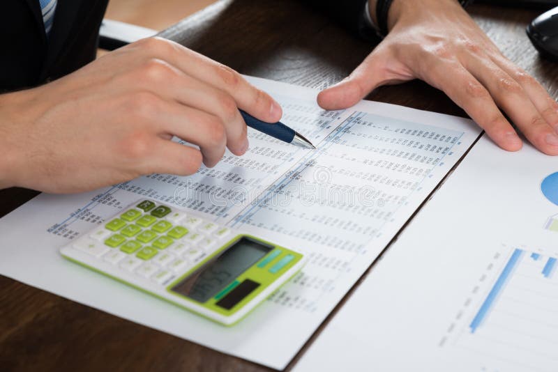 Close-up Of Businessperson Working With Accounting Document At Desk. Close-up Of Businessperson Working With Accounting Document At Desk