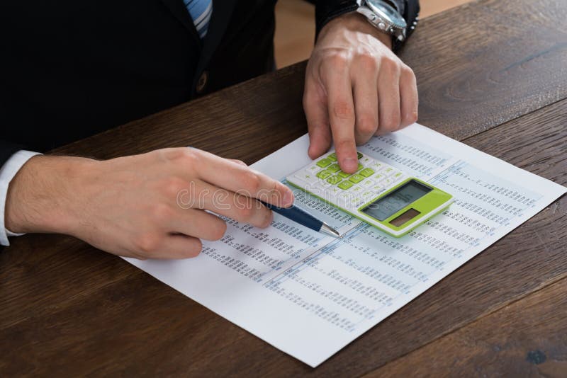 Close-up Of Businessperson Working With Accounting Document At Desk. Close-up Of Businessperson Working With Accounting Document At Desk