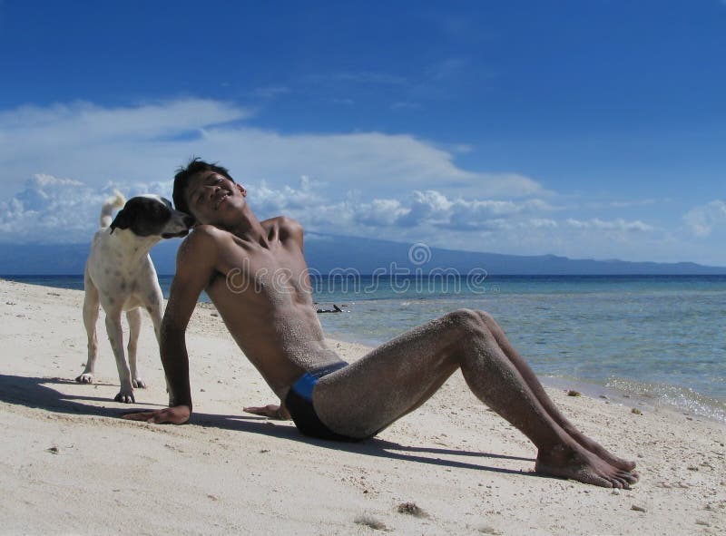 Dog meets boy on tropical beach.