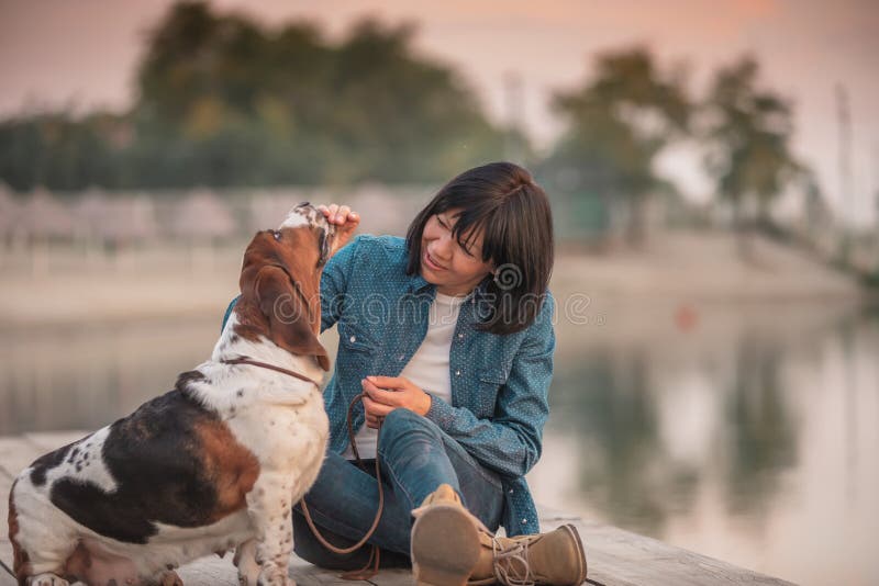 Dog with owner spend a day next to the river. Basset hound dog with owner spend a day next to the river playing and having fun - Image