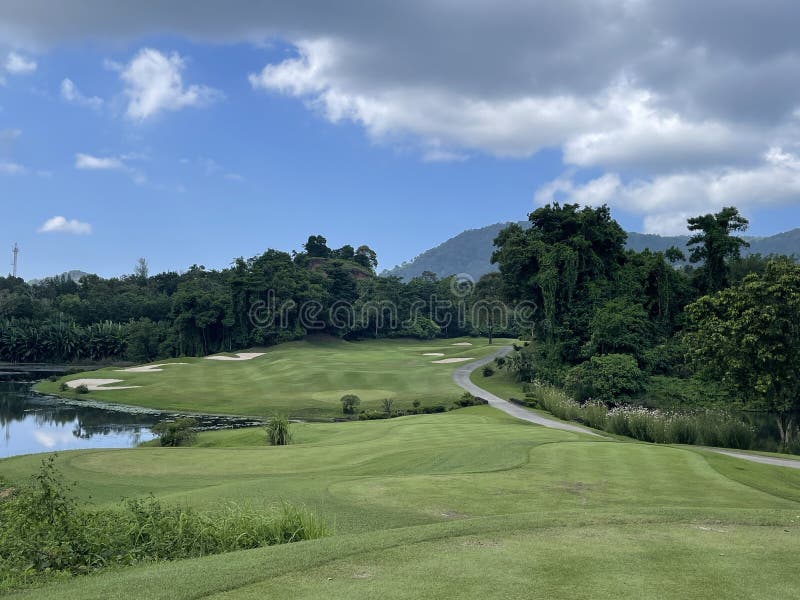 Tropic golf hole shot from the tee,a dogleg right around a lake with bunkers mountains and trees. Tropic golf hole shot from the tee,a dogleg right around a lake with bunkers mountains and trees