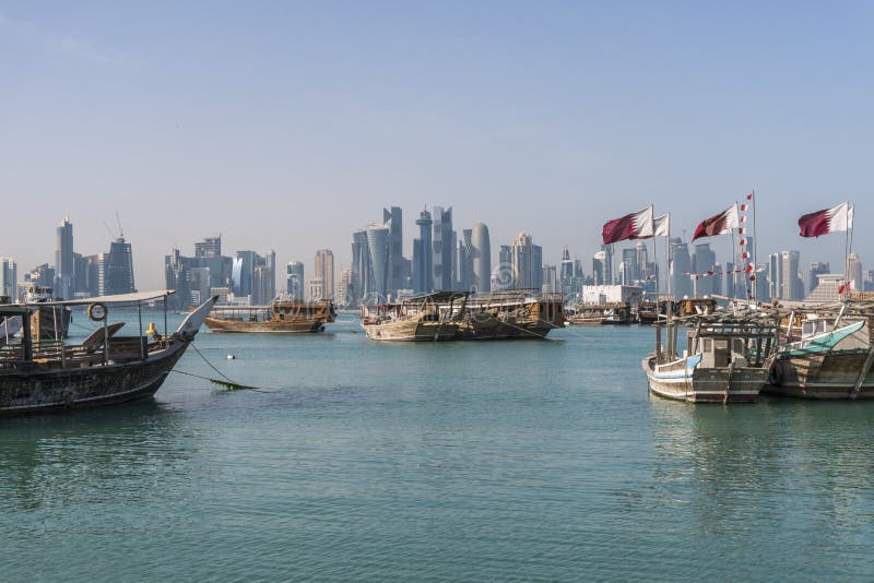 DOHA QATAR - Februari 2018: Härlig Doha horisontsikt med traditionella träfartyg med att sväva qatariska flaggor Corniche royaltyfria bilder DOHA QATAR - Februari 2018: Härlig Doha horisontsikt med traditionella träfartyg med att sväva qatariska flaggor Corniche royaltyfria bilder