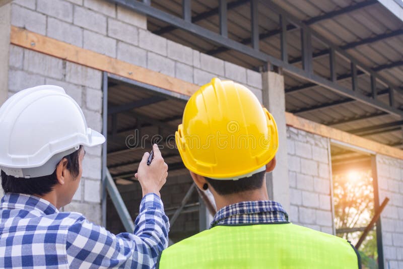 Doi bărbați pe șantier purtând pălării dure. stând și vorbind despre problemele construcției de locuințe royalty free stock photos