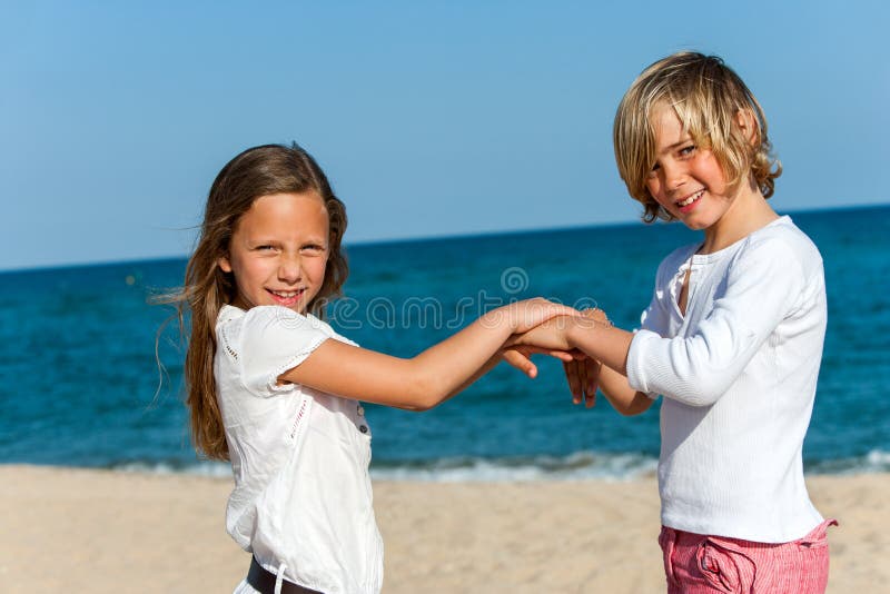 Doi prieteni jucând jocul manual pe plajă. stock image