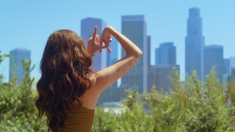 Doigts de fille inconnue faire signe la sur cityscape view. brunette debout dans le parc. banque de vidéos