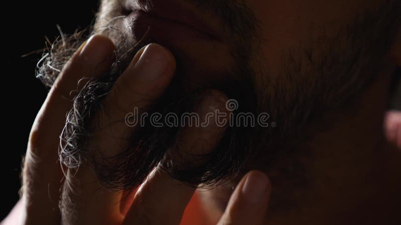 Doigts homme brassant barbe noire avec cheveux gris. closeup. fond sombre. vue latérale de la barbe à rayures avant banque de vidéos