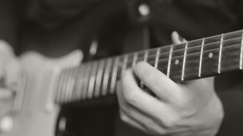 Doigts masculins jouant sur la guitare électrique, noire et blanche