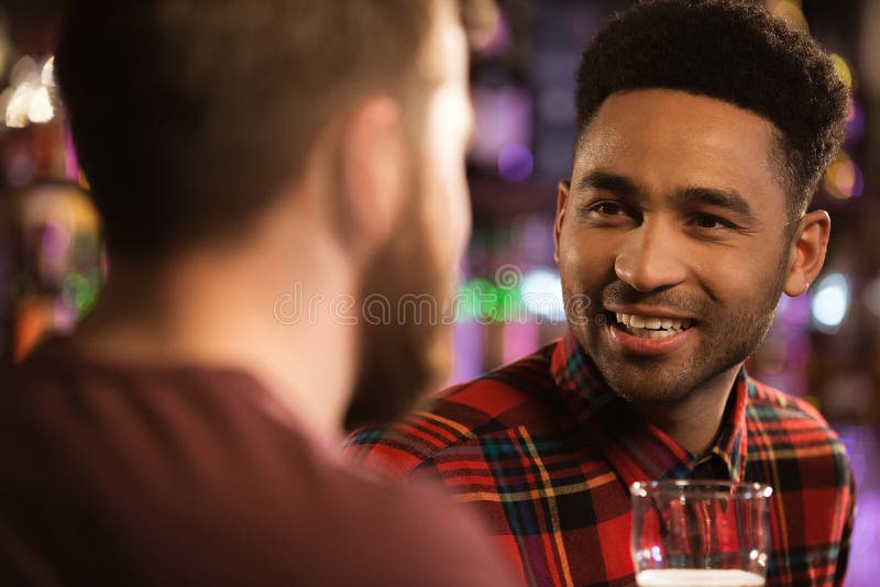 Dois amigos masculinos felizes que bebem a cerveja na barra foto de stock Dois amigos masculinos felizes que bebem a cerveja na barra foto de stock