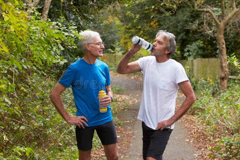 Dois basculadores masculinos maduros que tomam a ruptura enquanto na corrida foto de stock Dois basculadores masculinos maduros que tomam a ruptura enquanto na corrida foto de stock