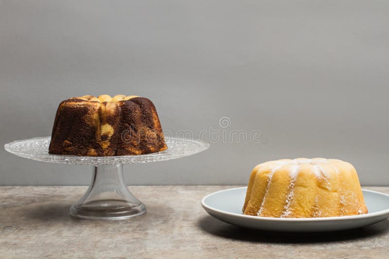 Dois bolos do bundt, um da baunilha e do chocolate e um do limão imagem de stock royalty free Dois bolos do bundt, um da baunilha e do chocolate e um do limão imagem de stock royalty free