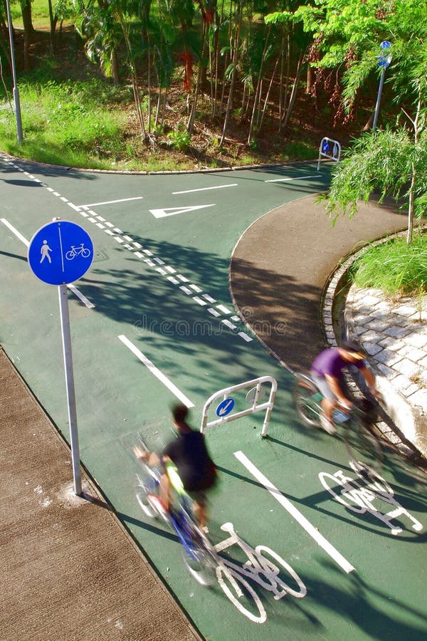 Dois cavaleiros da bicicleta que seguem os sinais de estrada imagens de stock Dois cavaleiros da bicicleta que seguem os sinais de estrada imagens de stock