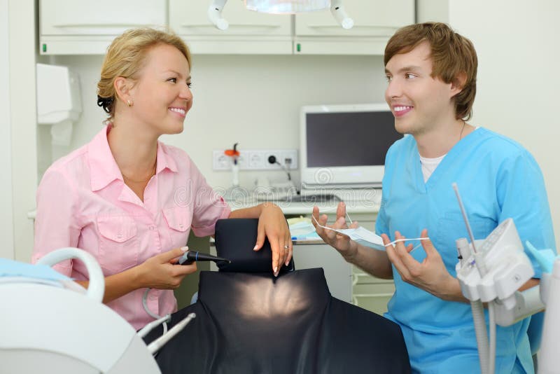 Dois dentistas sentam-se no gabinete da clínica dental