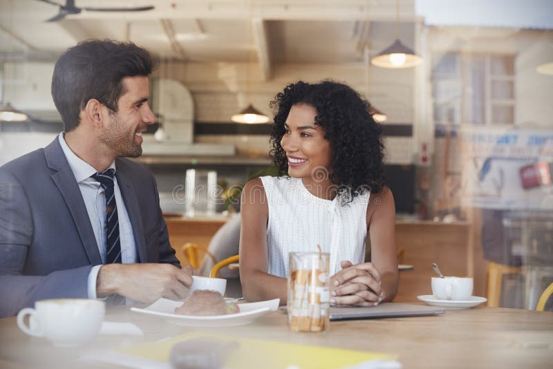 Dois empresários encontram-se na cafetaria disparada através da janela fotografia de stock Dois empresários encontram-se na cafetaria disparada através da janela fotografia de stock