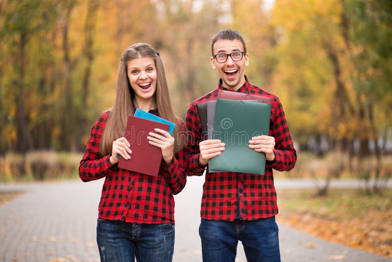 Dois estudantes entusiasmados felizes que aprovaram exames no outono imagens de stock Dois estudantes entusiasmados felizes que aprovaram exames no outono imagens de stock