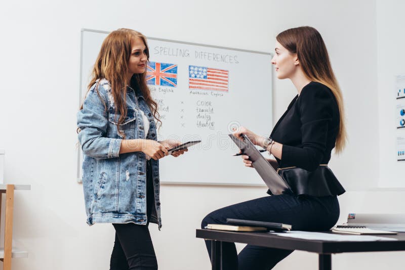 Dois estudantes fêmeas que falam na sala de aula Faculdade, escola de língua inglesa imagens de stock Dois estudantes fêmeas que falam na sala de aula Faculdade, escola de língua inglesa imagens de stock