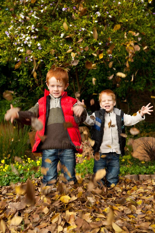 Dois felizes, irmãos de sorriso que jogam no lea do outono imagens de stock Dois felizes, irmãos de sorriso que jogam no lea do outono imagens de stock