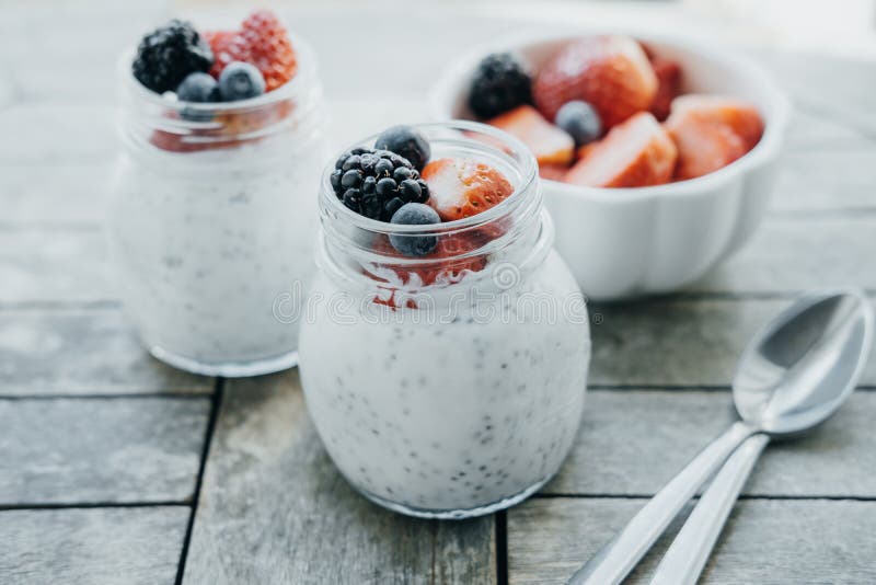 Dois frascos pequenos do pudim do chia, do iogurte e de frutos frescos: Strawb imagem de stock Dois frascos pequenos do pudim do chia, do iogurte e de frutos frescos: Strawb imagem de stock