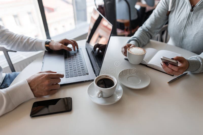 Dois freelancers bem sucedidos que sentam-se nos cafés que trabalham em um projeto criativo para uma xícara de café Close up das foto de stock Dois freelancers bem sucedidos que sentam-se nos cafés que trabalham em um projeto criativo para uma xícara de café Close up das foto de stock