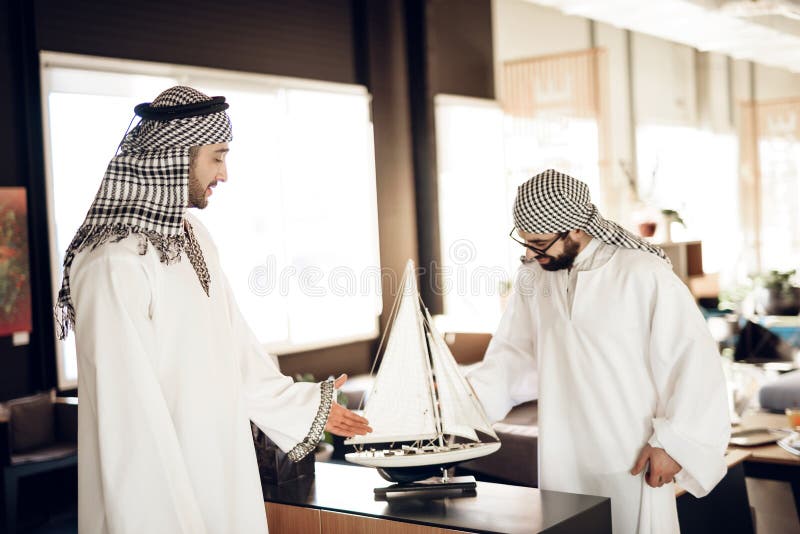 Dois homens de negócios árabes que jogam a xadrez na tabela na sala de hotel.