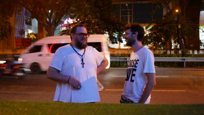 Dois homens estão falando. dois amigos numa caminhada noturna na cidade.