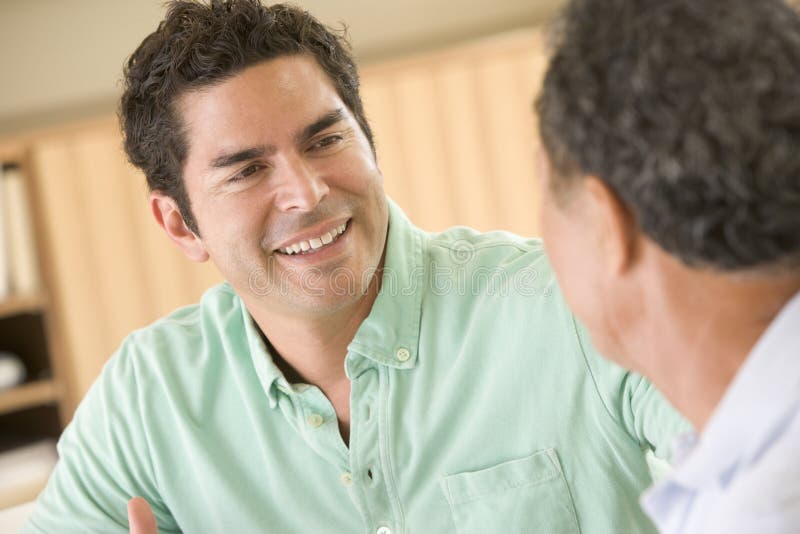 Dois homens que sentam-se na sala de visitas que fala e que sorri foto de stock Dois homens que sentam-se na sala de visitas que fala e que sorri foto de stock