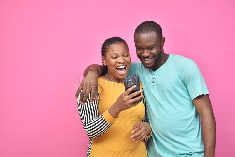 dois jovens amigos africanos, garoto e garota, que parecem animados enquanto veem algo em seus smartphones juntos foto de stock dois jovens amigos africanos, garoto e garota, que parecem animados enquanto veem algo em seus smartphones juntos foto de stock