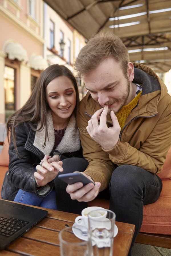 Dois jovens, 20-29 anos velhos, sentando-se no café junto, usando o smartphone no café fotografia de stock Dois jovens, 20-29 anos velhos, sentando-se no café junto, usando o smartphone no café fotografia de stock