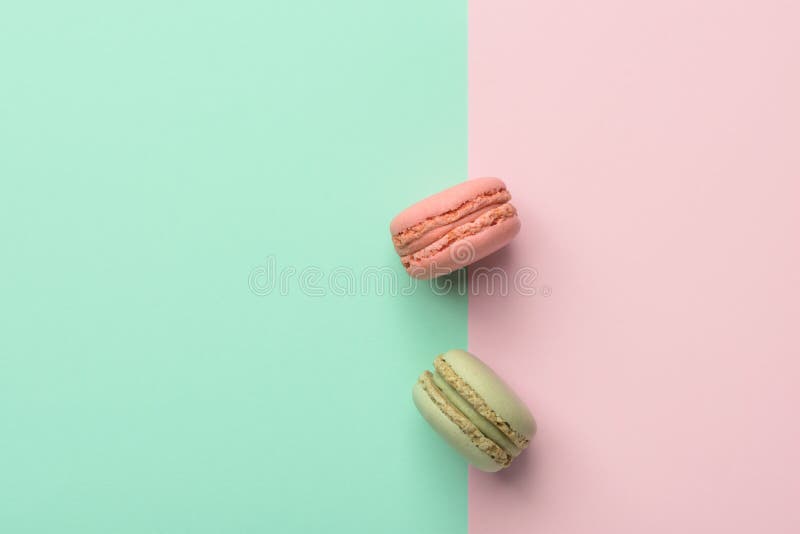 Dois macarons morango e sabor do pistache no fundo cor-de-rosa chartreuse verde pastel do duotone Confeitos da pastelaria frances