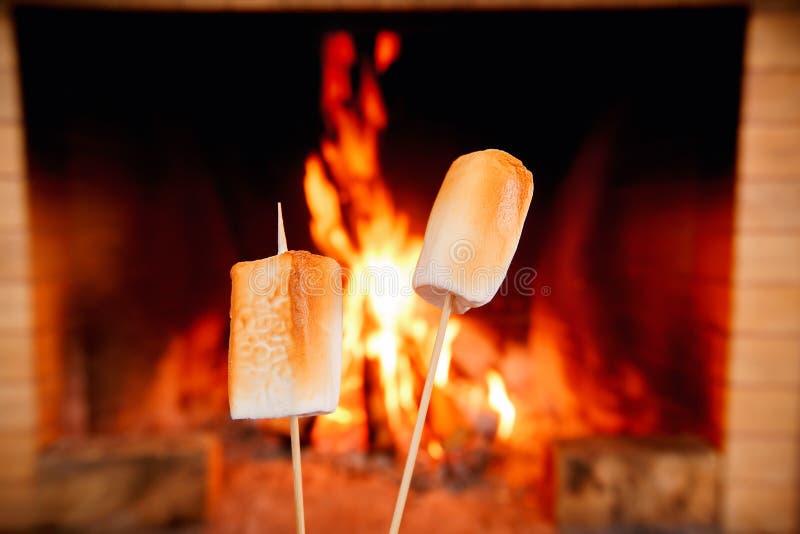 Dois marshmallows nas varas que estão sendo roasted pelo fogo fotografia de stock royalty free Dois marshmallows nas varas que estão sendo roasted pelo fogo fotografia de stock royalty free