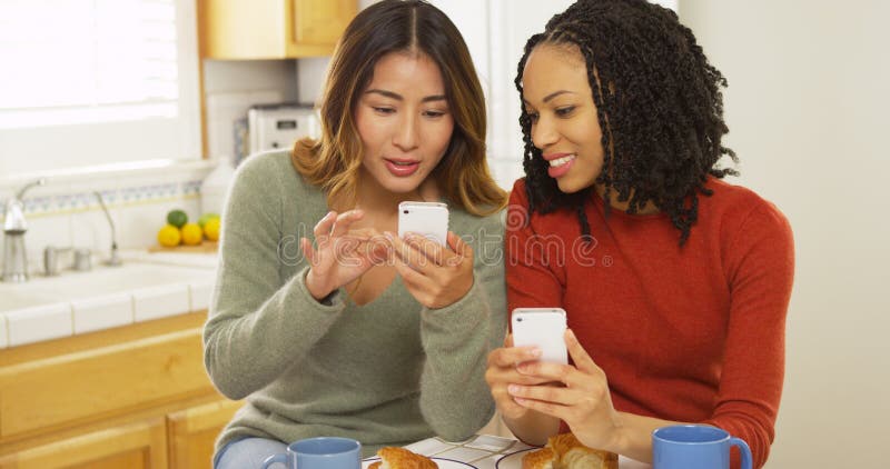 Dois Melhores Amigos Das Mulheres Que Usam Telefones Espertos E Comendo O Café Da Manhã Imagem