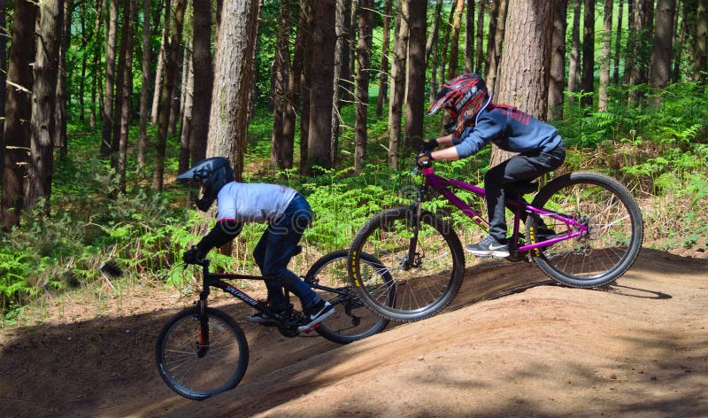 Dois meninos no curso em declive do Mountain bike nas madeiras imagens de stock Dois meninos no curso em declive do Mountain bike nas madeiras imagens de stock