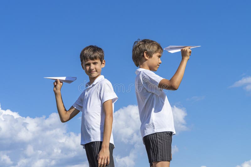 Dois meninos que mantêm planos do Livro Branco contra o céu azul fotografia de stock royalty free Dois meninos que mantêm planos do Livro Branco contra o céu azul fotografia de stock royalty free