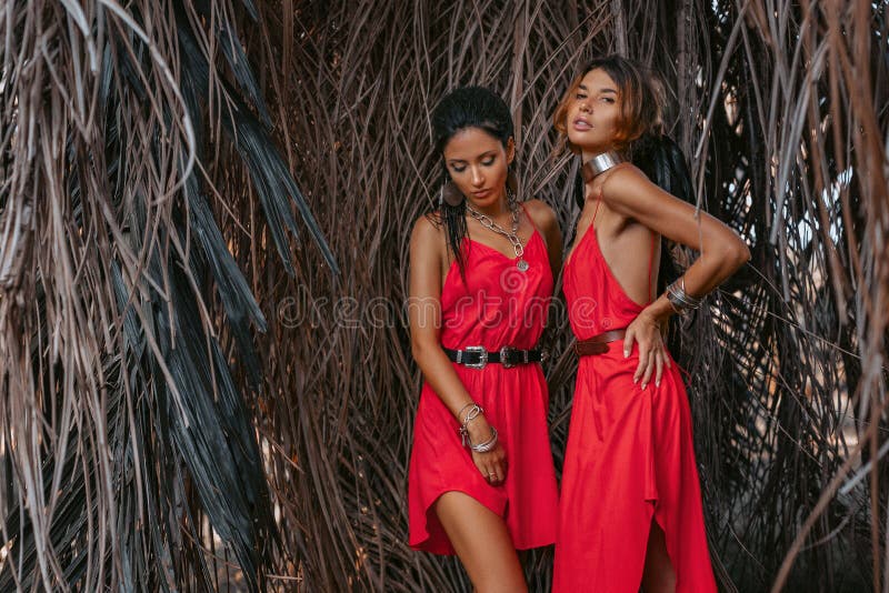 Dois modelos elegantes novos bonitos em vestidos vermelhos fora no por do sol imagens de stock Dois modelos elegantes novos bonitos em vestidos vermelhos fora no por do sol imagens de stock