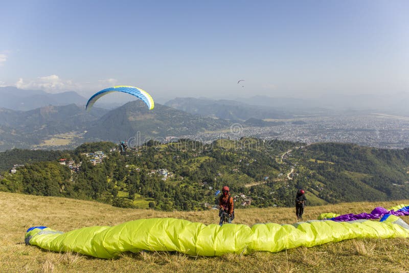 Dois paragliders no montanhês antes de decolar contra o contexto de um vale da montanha e de voar fotos de stock royalty free Dois paragliders no montanhês antes de decolar contra o contexto de um vale da montanha e de voar fotos de stock royalty free