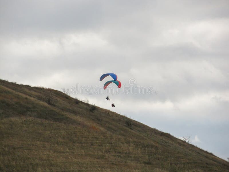 Dois paragliders que flutuam no ar acima de uma montanha alta foto de stock royalty free Dois paragliders que flutuam no ar acima de uma montanha alta foto de stock royalty free