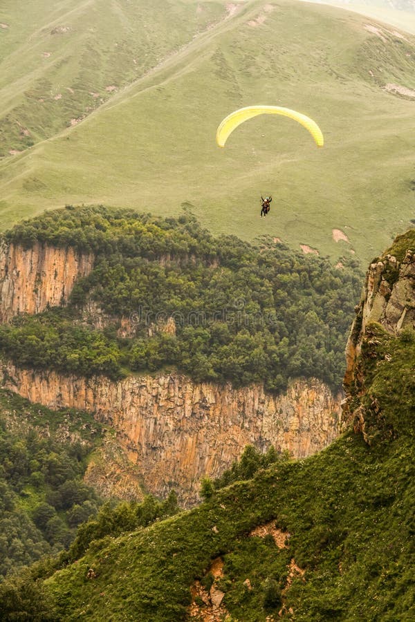Dois parapentes voam em paralelo sobre as montanhas e os montes selvagens das montanhas do Cáucaso inferior na Geórgia imagem de stock Dois parapentes voam em paralelo sobre as montanhas e os montes selvagens das montanhas do Cáucaso inferior na Geórgia imagem de stock