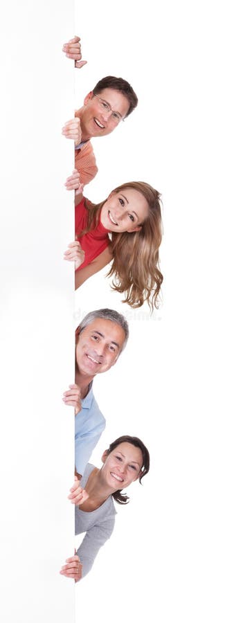 Dois pares felizes que sustentam uma placa vazia fotografia de stock Dois pares felizes que sustentam uma placa vazia fotografia de stock