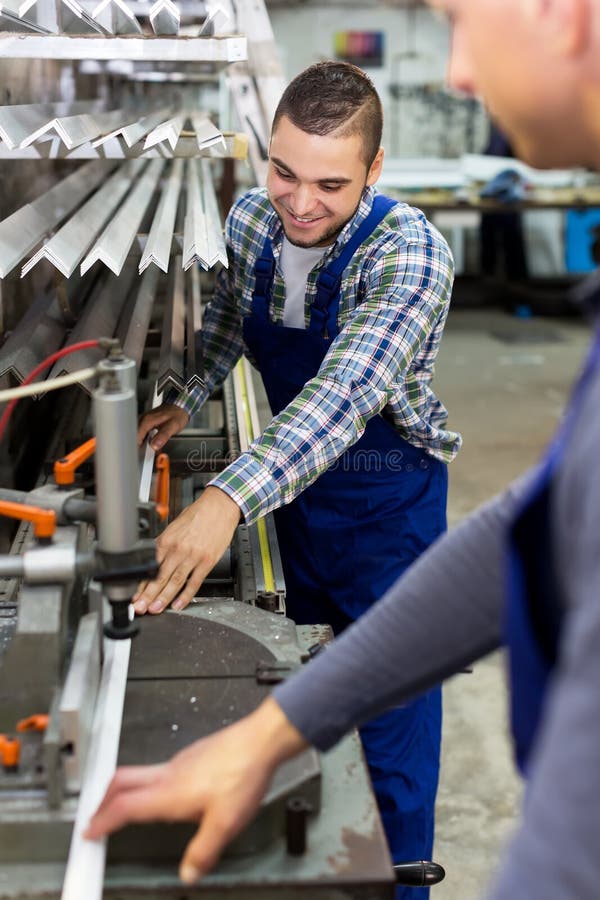 Dois trabalhadores que trabalham em uma máquina imagens de stock Dois trabalhadores que trabalham em uma máquina imagens de stock