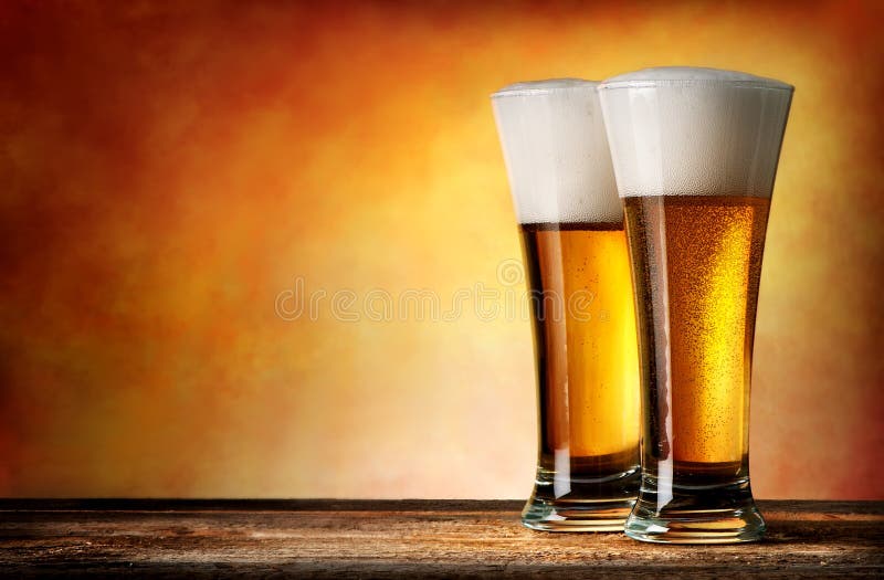 Two glasses of beer on a yellow background. Two glasses of beer on a yellow background
