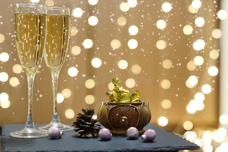 Dois vidros do champanhe e dos chocolates no fundo de festões festivas, quedas brancas da neve imagem de stock royalty free Dois vidros do champanhe e dos chocolates no fundo de festões festivas, quedas brancas da neve imagem de stock royalty free