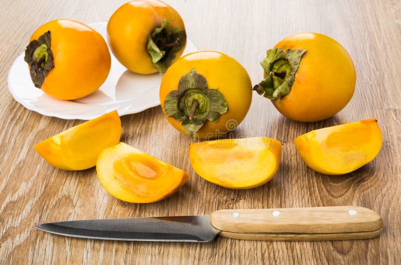 Dojrzali persimmons w talerzu, kawałki persimmon i kuchenny nóż, obrazy royalty free Dojrzali persimmons w talerzu, kawałki persimmon i kuchenny nóż, obrazy royalty free