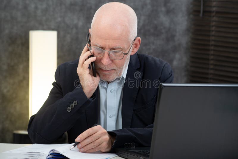 Dojrzały biznesmen opowiada z telefonem w biurze z brodą fotografia stock Dojrzały biznesmen opowiada z telefonem w biurze z brodą fotografia stock