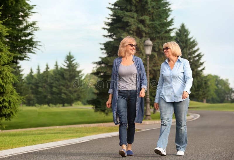 Mature women walking in park on sunny day. Mature women walking in park on sunny day