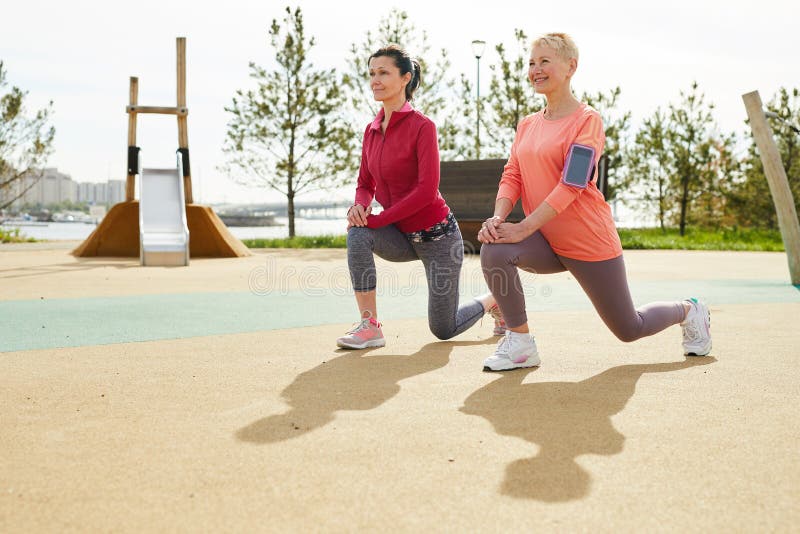 Full length portrait of two smiling mature women enjoying fitness workout outdoors in sunlight, copy space. Full length portrait of two smiling mature women enjoying fitness workout outdoors in sunlight, copy space