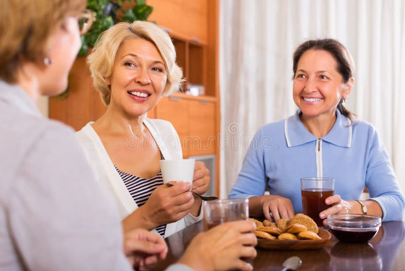 Happy mature women having coffee break at office. Focus on blonde woman. Happy mature women having coffee break at office. Focus on blonde woman