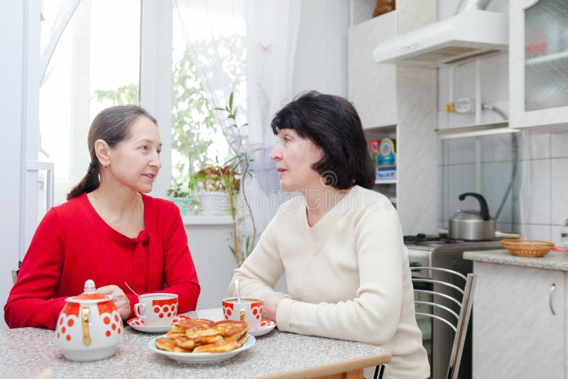 Two mature women talking at kitchen table with cup of tea. Two mature women talking at kitchen table with cup of tea.