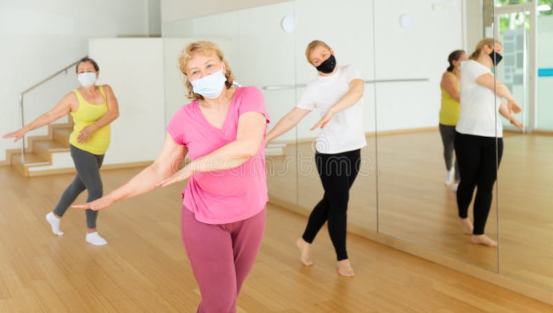 Active mature women wearing face masks for disease prevention enjoying training in dance studio, dance class for adults during coronavirus outbreak. Active mature women wearing face masks for disease prevention enjoying training in dance studio, dance class for adults during coronavirus outbreak