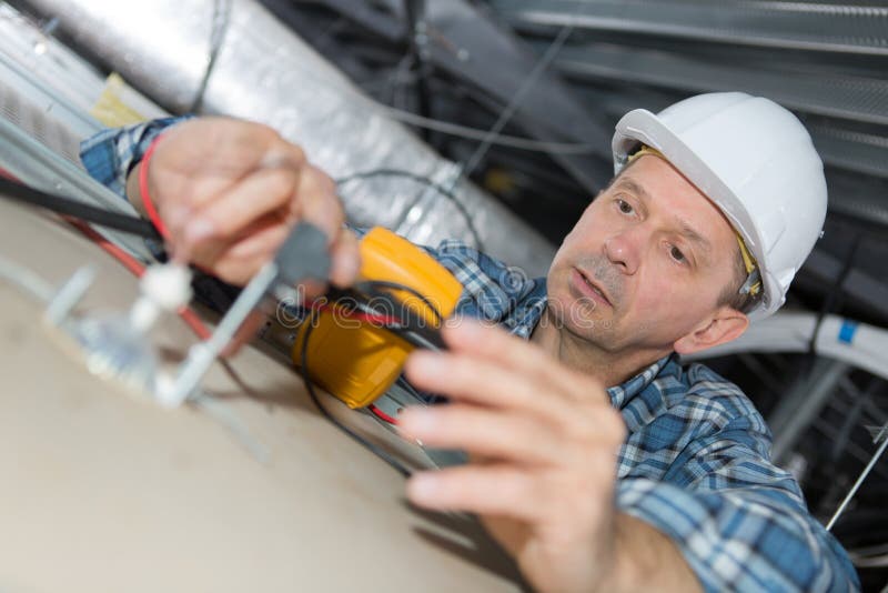 Dojrzały elektryk sprawdza budynek instalację elektryczną w suficie obraz stock Dojrzały elektryk sprawdza budynek instalację elektryczną w suficie obraz stock