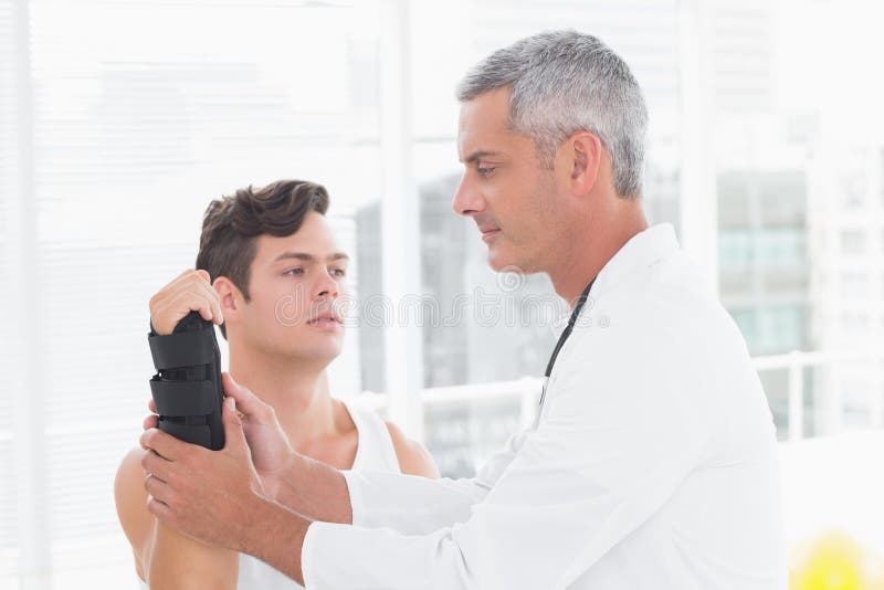 Doktor, der ein Mannhandgelenk überprüft stockbilder