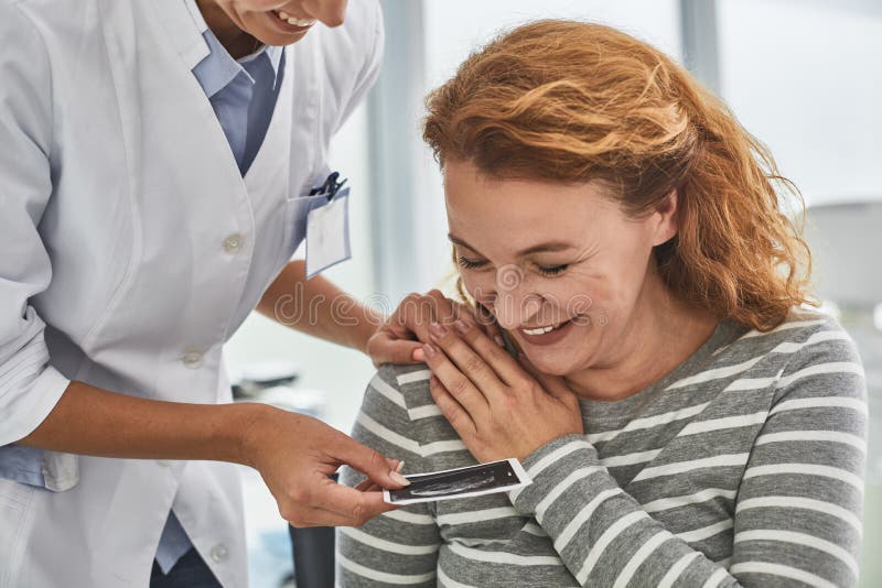 Doktor, der der glücklichen Mutter Ultraschallbabybild zeigt lizenzfreies stockbild Doktor, der der glücklichen Mutter Ultraschallbabybild zeigt lizenzfreies stockbild